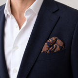 Midnight Copper Paisley Silk Pocket Square — Navy jacket · rounded puff