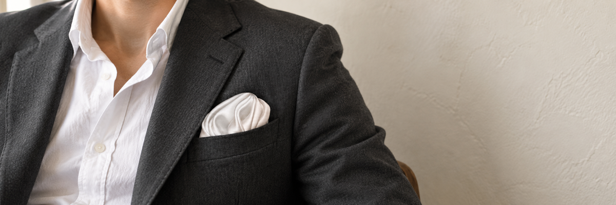 Pearl-white pocket square worn naturally in a textured navy jacket.