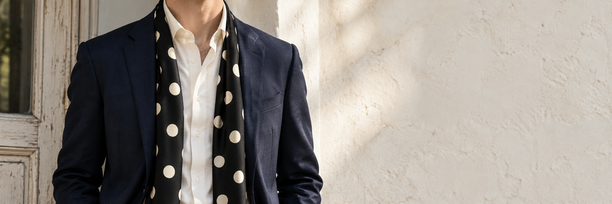 Black scarf with small cream polka dots worn naturally with a jacket.
