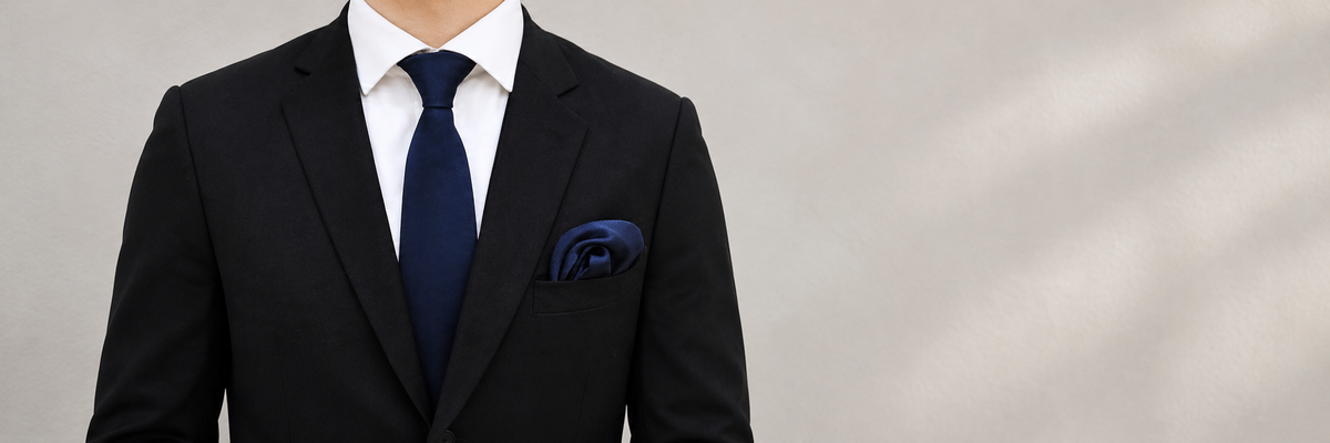 Navy tie and matching pocket square worn naturally with a jacket.