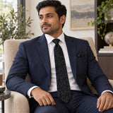 Onyx Damask Scroll silk tie and matching pocket square — Navy suit · seated lifestyle